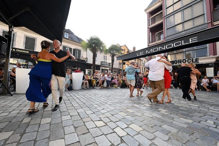 Des couples en train de danser le tango devant des cafés de Tarbes